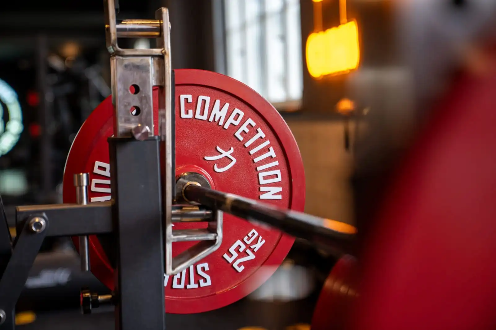 Closeup of a barbell on a rack with powerlifting competition plates loaded